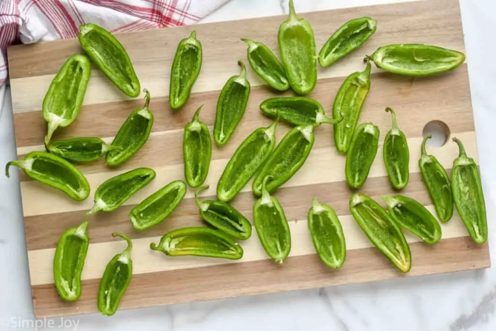 overhead view of jalapeño peppers cut in half and deseeded on a cutting board