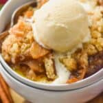 two white bowls stacked holding easy apple crisp recipe topped with ice cream