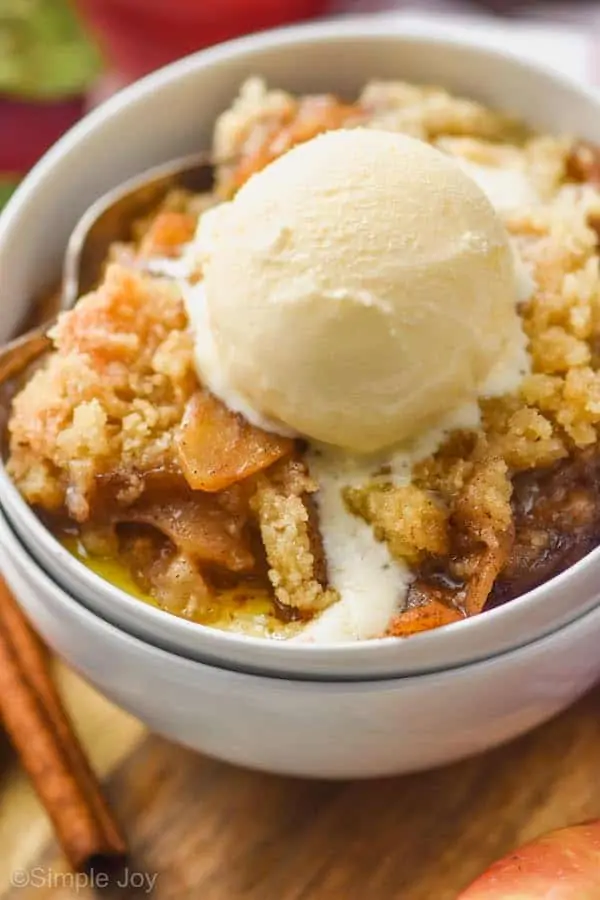 two white bowls stacked holding easy apple crisp recipe topped with ice cream