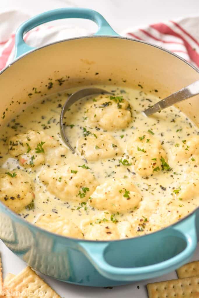 teal dutch oven full of easy chicken and dumplings garnished with fresh parsley