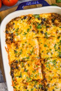 close up overhead of easy enchilada casserole in a baking dish that has been cut into pieces