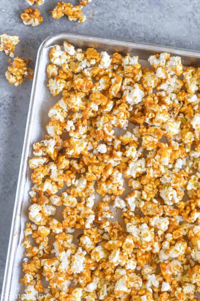 overhead view of a rimmed baking sheet lined with parchment paper with homemade caramel corn on it