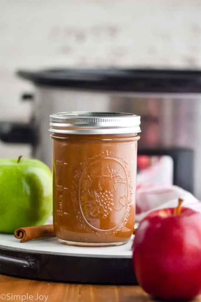 a mason jar full of applesauce in front of a slow cooker