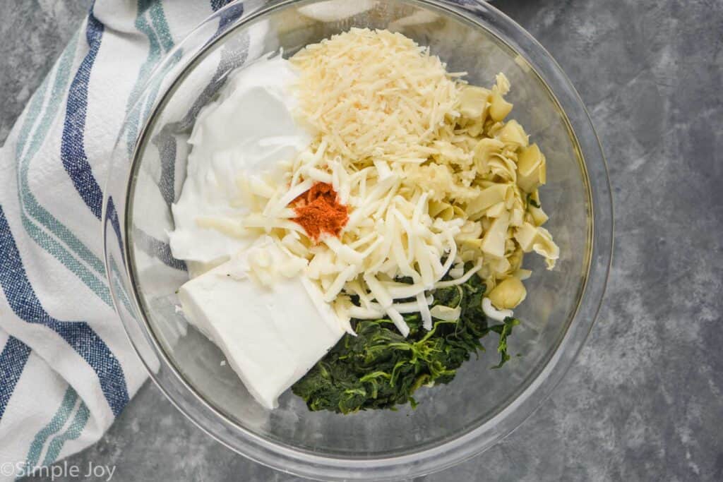 overhead view of a mixing bowl full of ingredients for spinach artichoke dip