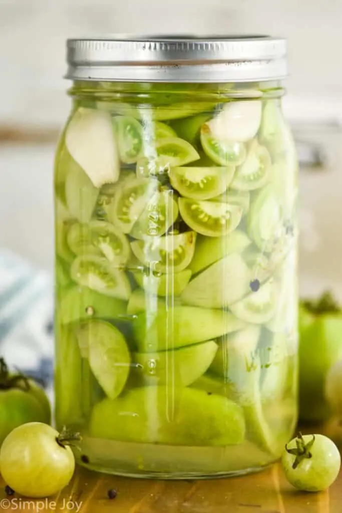 a mason jar full of pickled green tomatoes