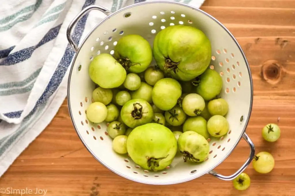 overhead view view of a colander full of green tomatoes