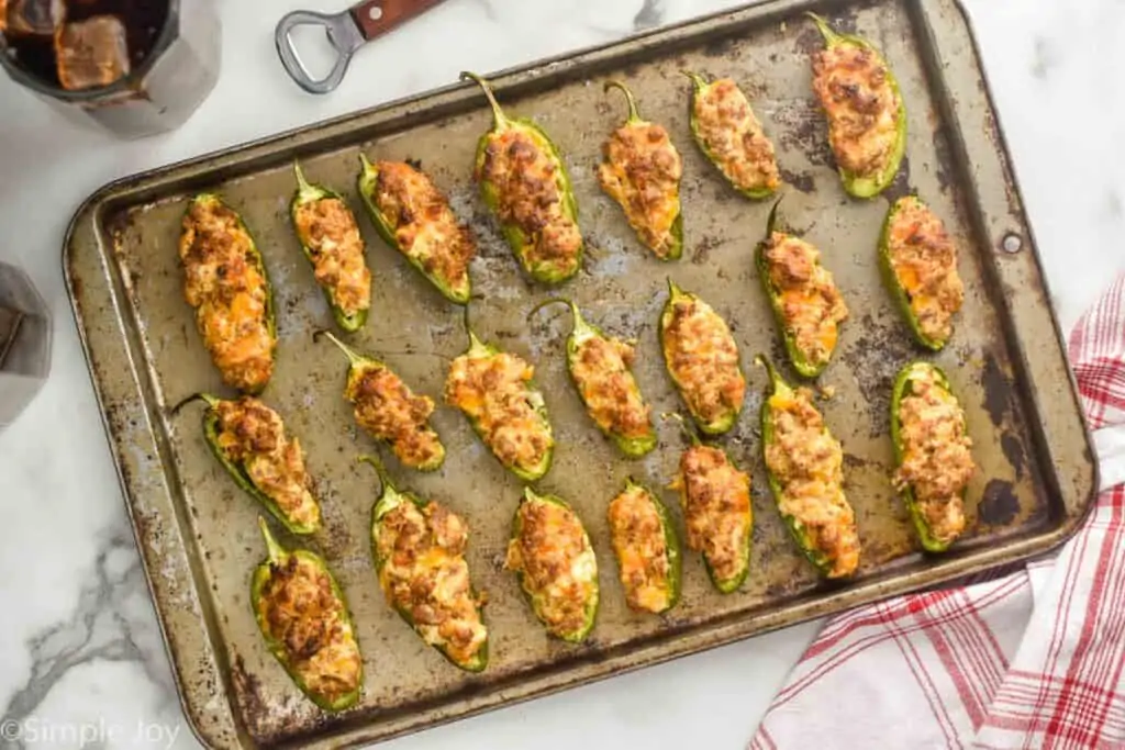 overhead view of a rimmed baking sheet with sausage stuffed jalapeños