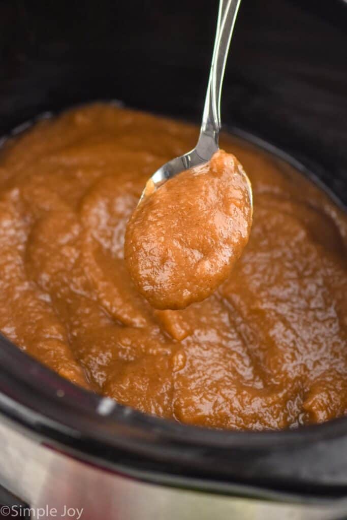 a spoonful of slow cooker applesauce coming out of a crockpot