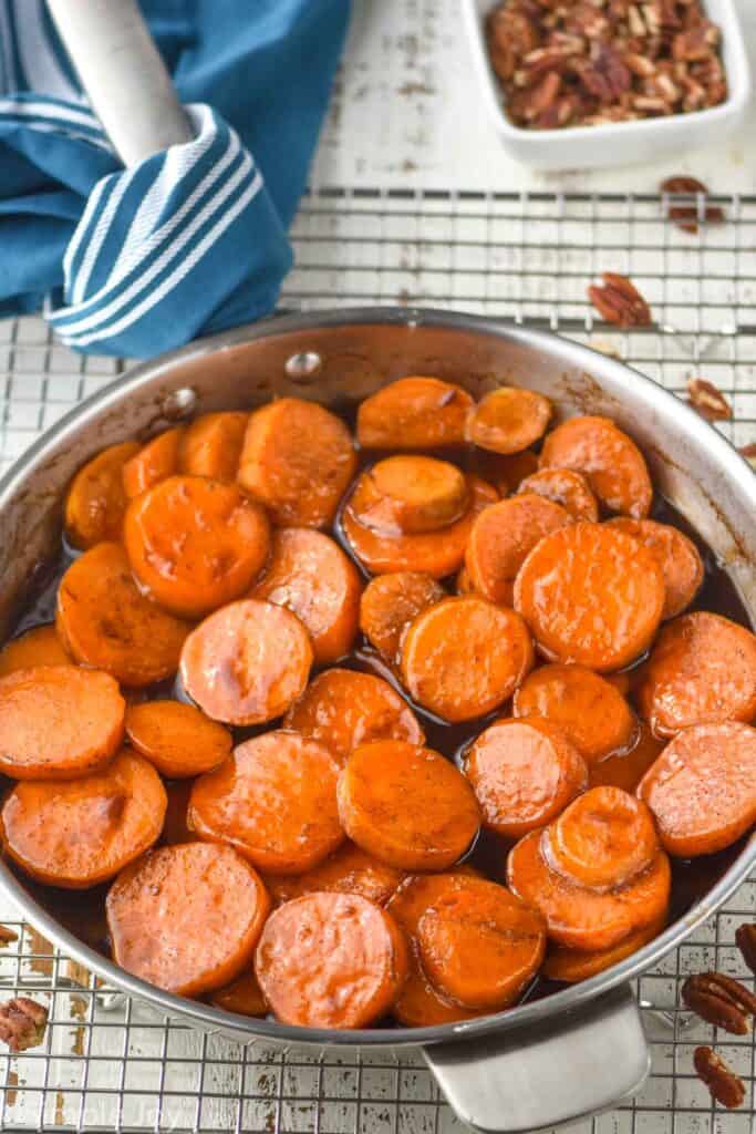 skillet with candied sweet potato recipe, surrounded by pecans