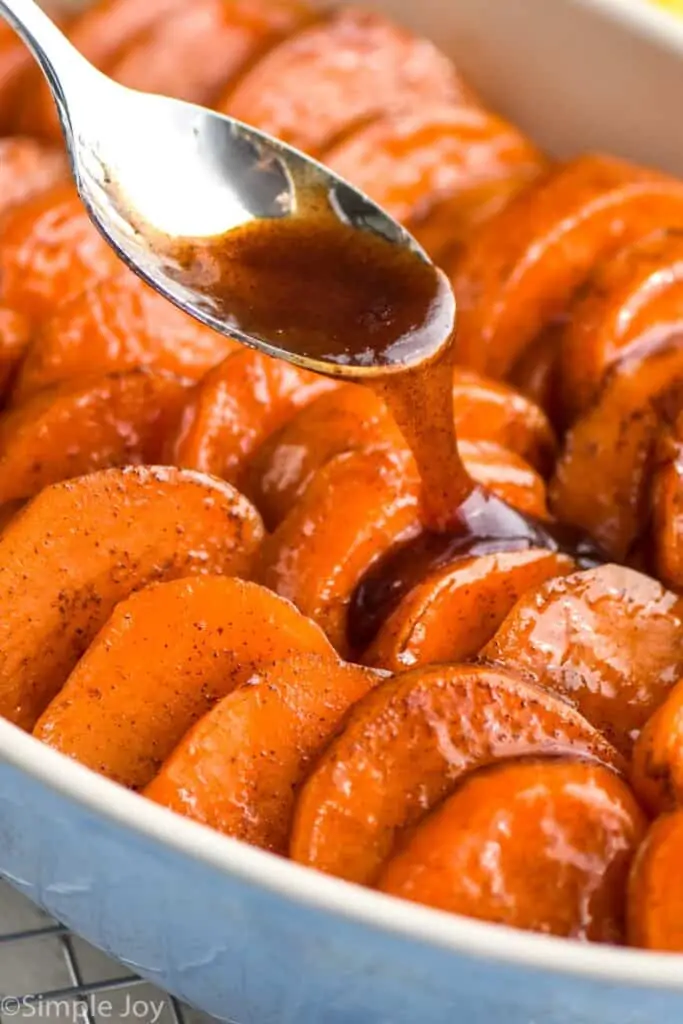 syrupy mixture being poured over casserole dish with candied sweet potatoes