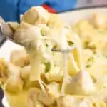 spoonful of Alfredo chicken casserole being pulled out of a skillet