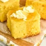 piece of cornbread on a cutting board topped with butter and honey