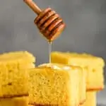 honey wand dripping honey over two pieces of stacked cornbread