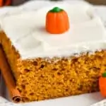 close up picture of a piece of pumpkin cake topped with cream cheese frosting on a plate