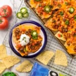 overhead look at sheet pan nachos next to a small plate of nachos, an open bag of Tostitos and a jar of Tostitos salsa