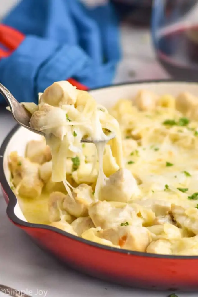 spoonful of Alfredo chicken casserole being pulled out of a skillet