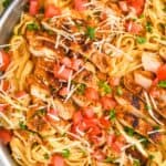 overhead close up view of cajun chicken Alfredo with sliced chicken on top of fettucine garnished with fresh tomatoes, parsley, and parmesan - 12