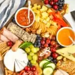 an overhead view of a charcuterie board with cheeses, meats, crackers, vegetables, fruits, and nuts