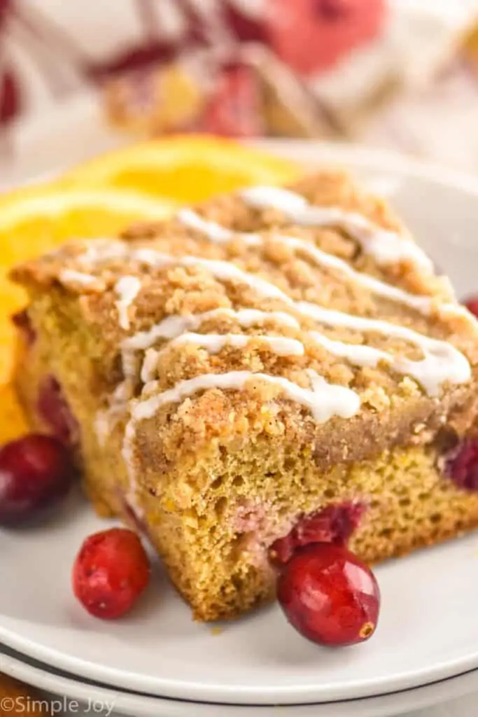 a piece of cranberry orange coffee cake up close on a plate with icing drizzled on top