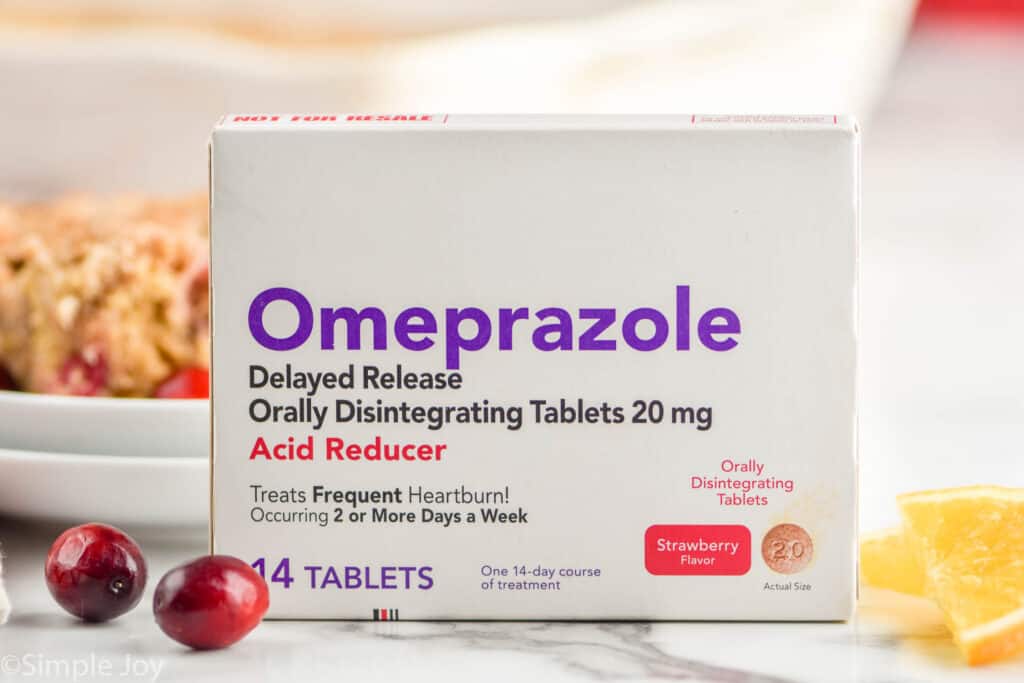 a box of ompeprazole odt next to two cranberries