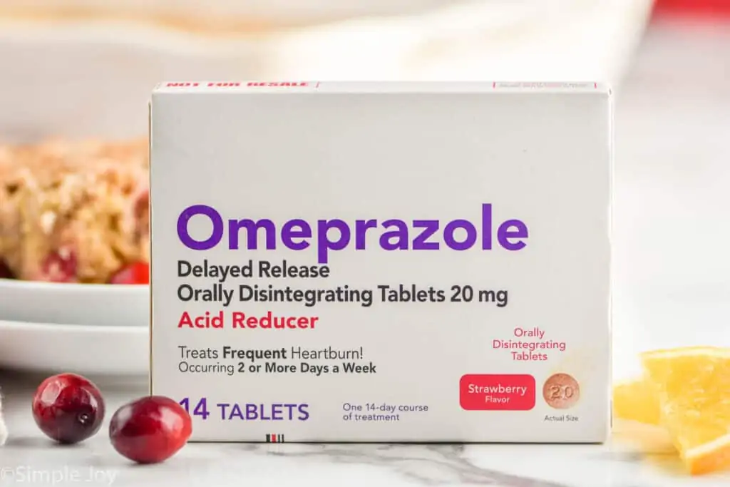 a box of ompeprazole odt next to two cranberries