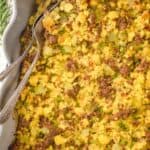 overhead view of a baking dish with cornbread stuffing recipe with two utensils sticking put