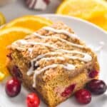 piece of cranberry orange coffee cake that has had icing drizzled across the top of it