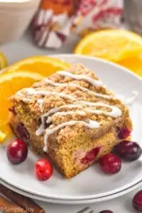 piece of cranberry orange coffee cake that has had icing drizzled across the top of it