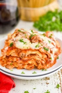 side view of a piece of crockpot lasagna garnished with fresh parsley