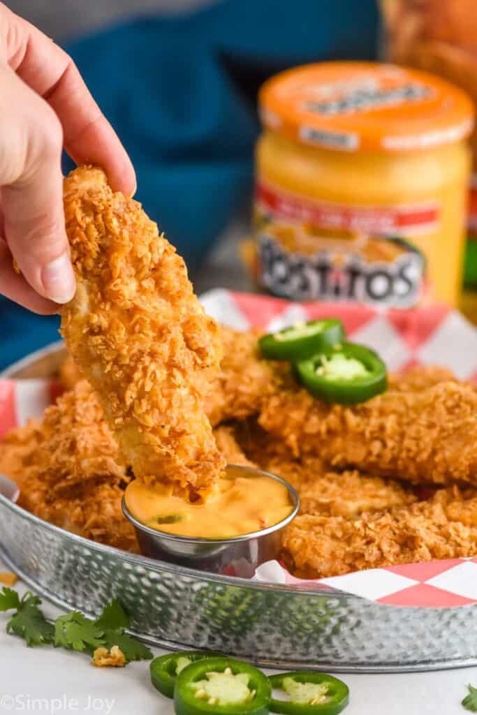 chicken strip being dipped into nacho cheese sauce