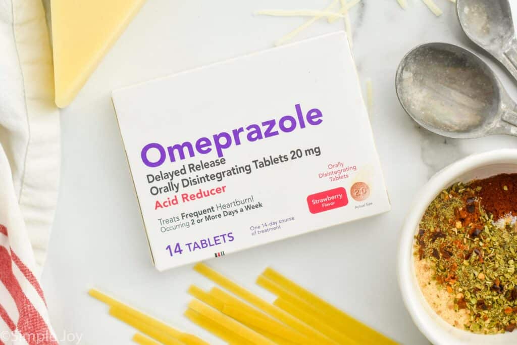 box of omeprazole odd next to cajun seasoning, uncooked fettuccine, and parmesan cheese