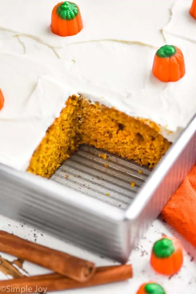 close up of a pumpkin cake in a metal baking dish that has been cut into