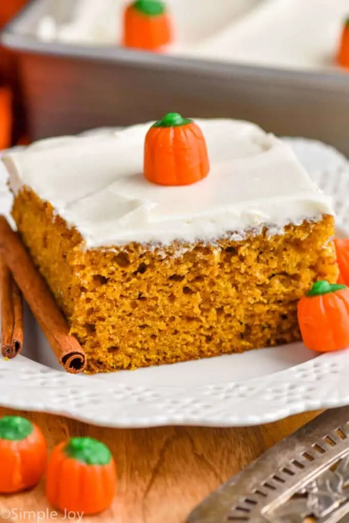 close up picture of a piece of pumpkin cake topped with cream cheese frosting on a plate