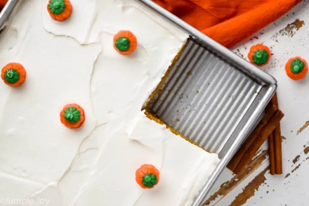 overhead view of a pumpkin spice cake in a baking dish topped with cream cheese frosting and small pumpkin candies