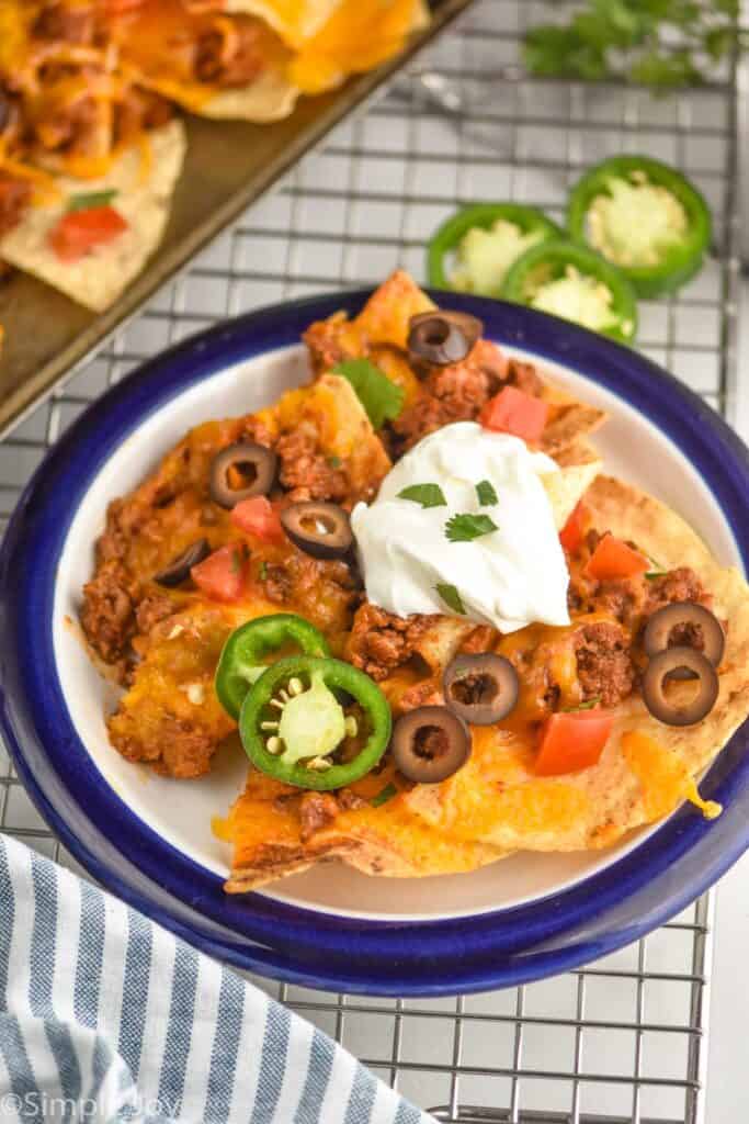small plate full of nachos and topped with sour cream