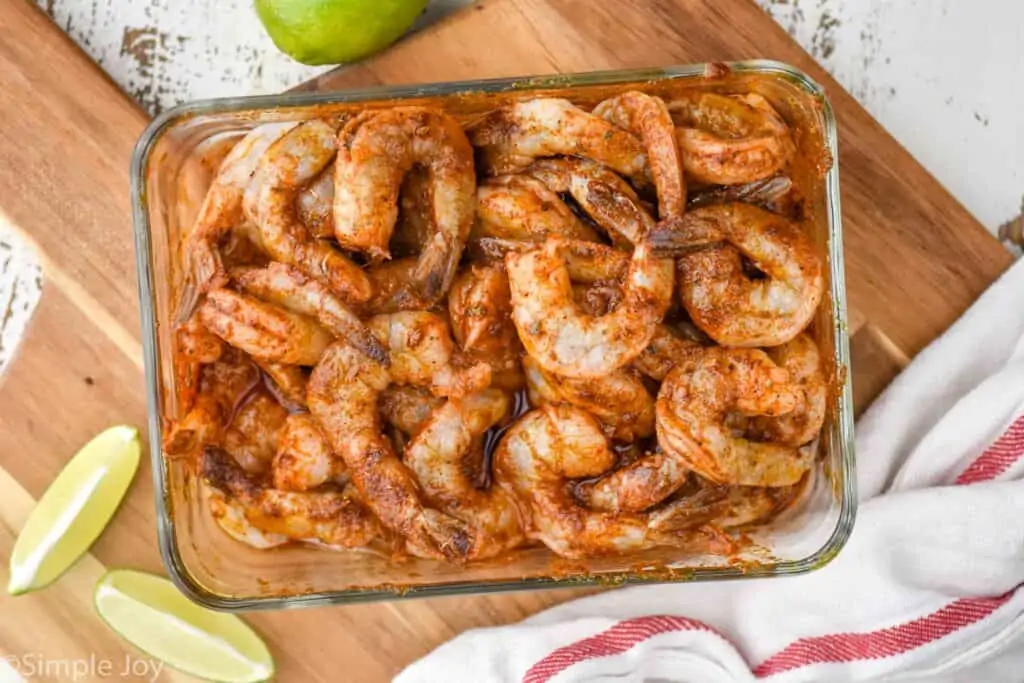 overhead view of shrimp marinating in shrimp fajita seasoning in a glass container