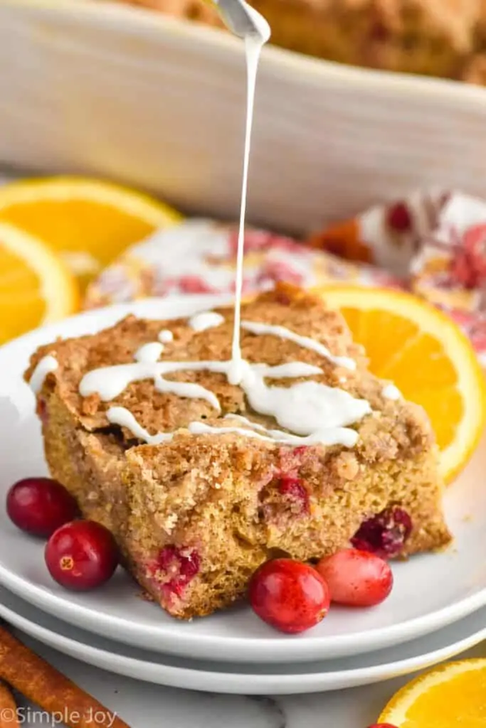 a piece of cranberry orange sour cream coffee cake having icing drizzled on it