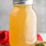 a mason jar full of turkey broth on a cutting board surrounded by fresh herbs - 7