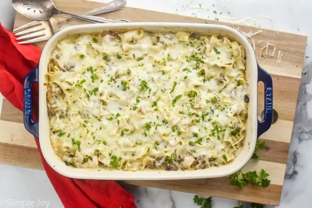 overhead photo of a baking dish full of turkey tetrazzini garnished with fresh parsley and parmesan