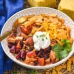 a small bowl full of turkey tortilla soup garnished with tortilla strips, sour cream, cheese, and cilantro - 6
