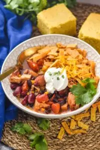 a small bowl full of turkey tortilla soup garnished with tortilla strips, sour cream, cheese, and cilantro