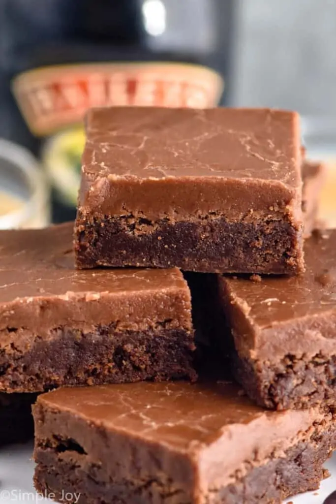 a small pile of baileys brownies with the bottle of baileys in the background