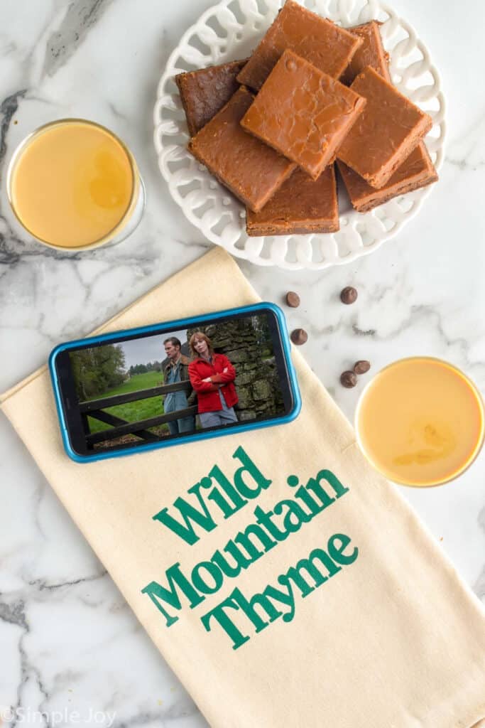 overhead view of a plate of baileys brownies, a napkin that reads "wild mountain thyme" and a phone playing the movie