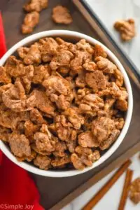 overhead view of candied walnuts in a big white bowl on a tray