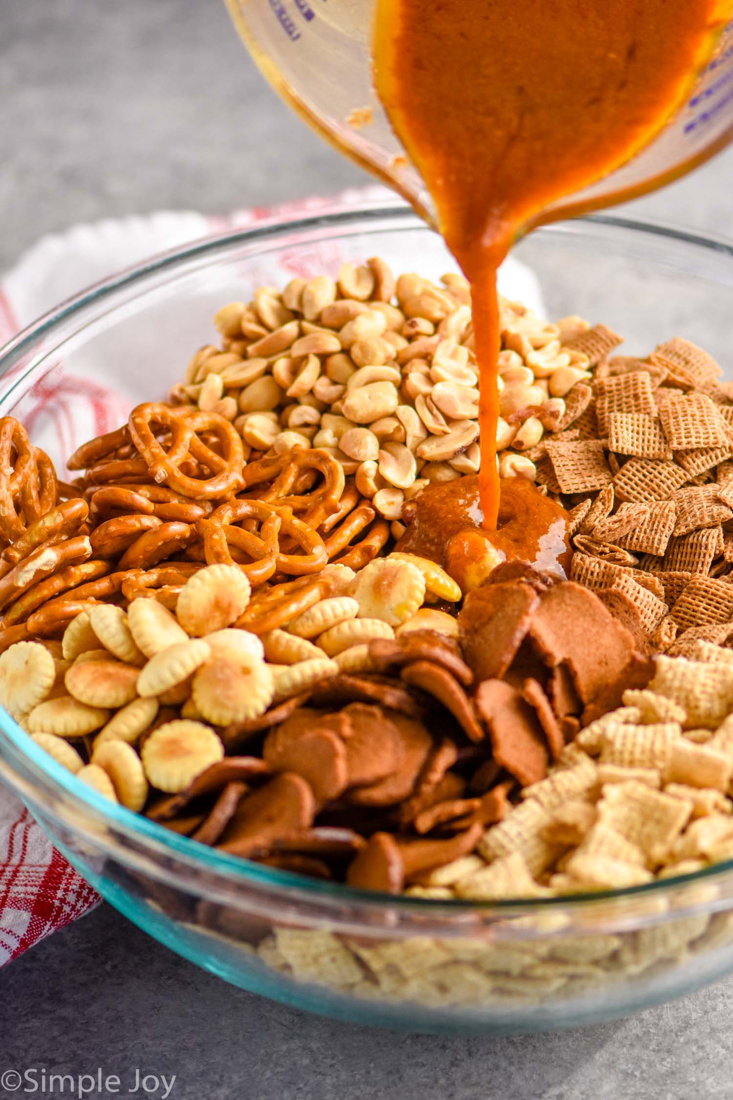 Chex mix seasoning being poured over the ingredients