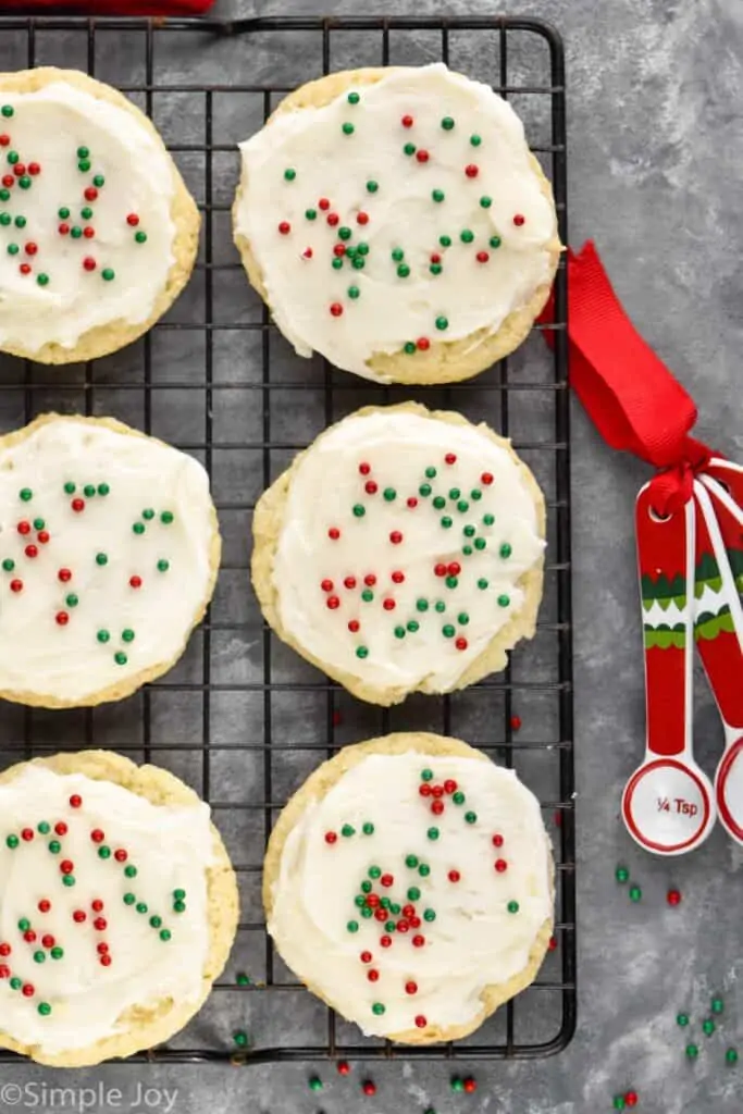 overhead view of 6 sour cream cookies that are frosted and on a cooling rack with red and green sprinkles