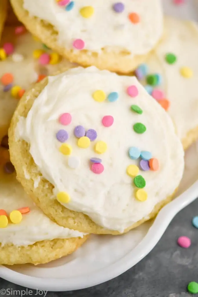 close up of a sour cream cookie on a plate that has been frosted and decorated with sprinkles