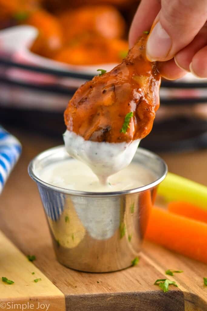 air fryer chicken drumstick being dipped in ranch dressing
