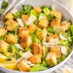 side view of a Caesar salad in a bowl with large croutons and peels of Parmesan cheese - 10