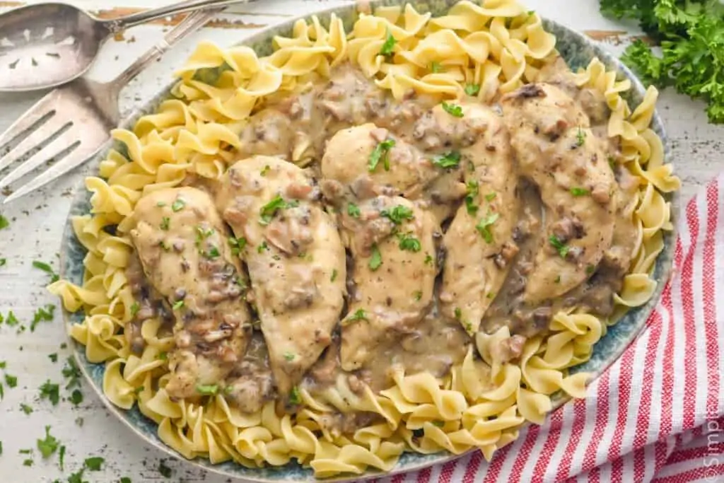 overhead of a platter of noodles topped with cream of mushroom soup over chicken tenders